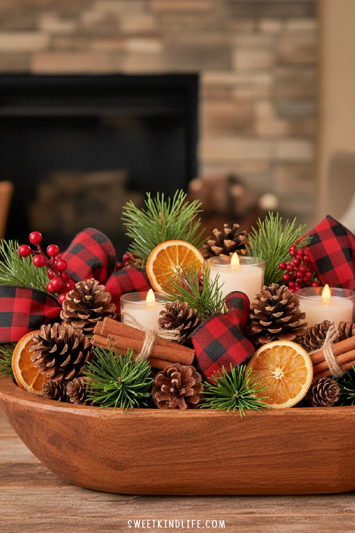 rustic coffee table christmas decor with a wooden bowl of plaid bows, pinecones, orange slices, cinnamon sticks and candles