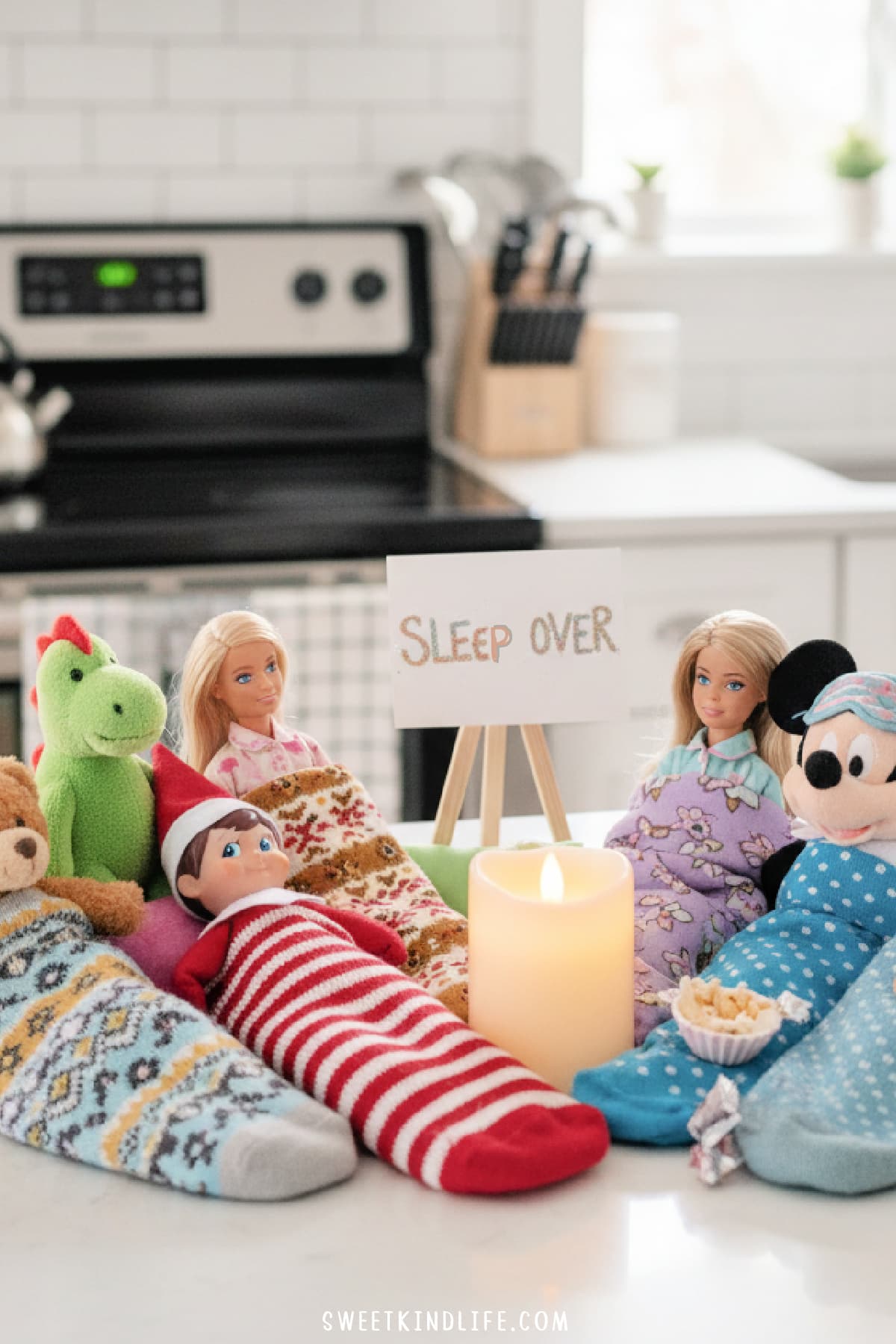 an elf on the shelf in a sock with other toys in socks for a sleepover in the kitchen