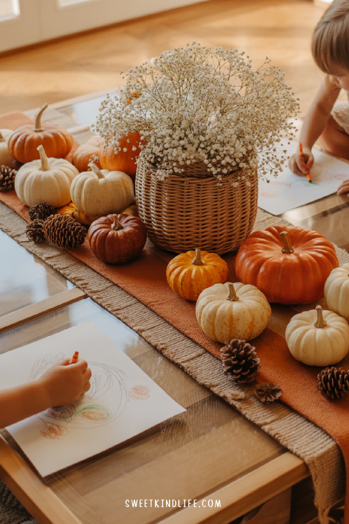 fall coffee table decor featuring pumpkins, basket with flowers and kids coloring