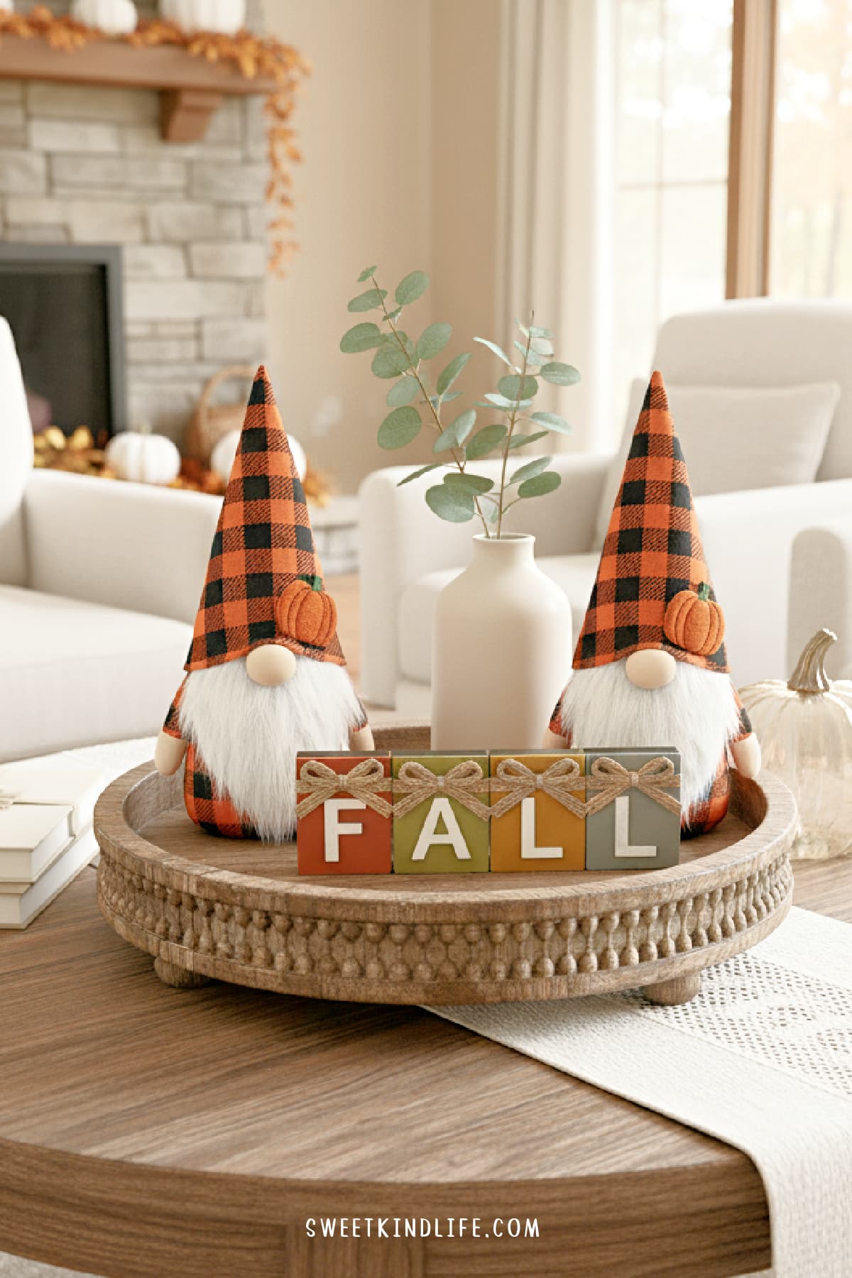 a photo of a living room with a wooden tray with fall gnomes, fall sign, simple vase, glass pumpkin and books